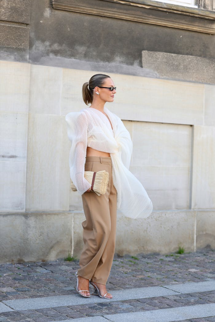 about-us-02 Stylish woman in urban Copenhagen showcasing modern fashion with sheer blouse and clutch.