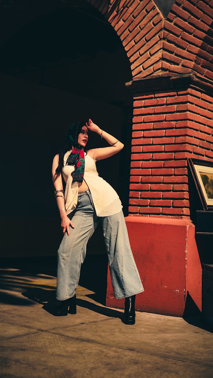services-02 Stylish woman posing confidently against a brick archway in urban setting.